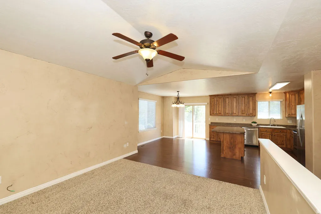 Open-concept living space featuring vaulted ceilings and a ceiling fan with integrated lighting