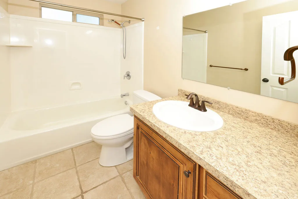 Bathroom featuring a wood-finish vanity with an integrated sink and a speckled countertop