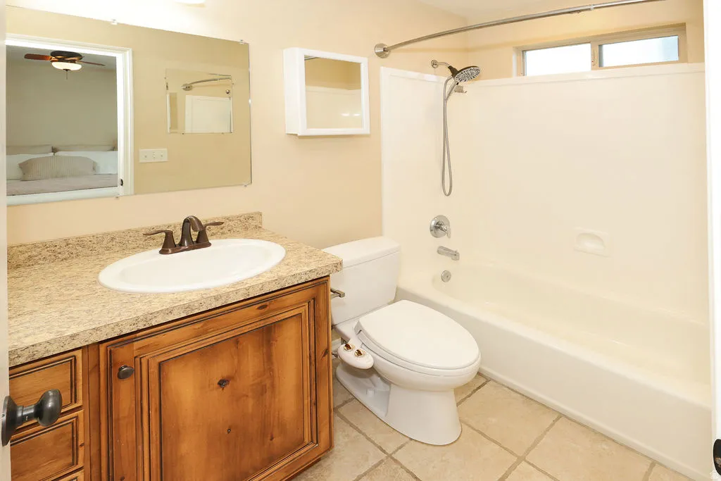 Bathroom featuring a wood-finish vanity with a light-toned countertop, an oval undermount sink, and a bronze-finish faucet