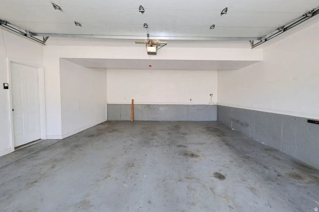 Spacious garage featuring a concrete floor, painted walls, overhead lighting, and an internal access door