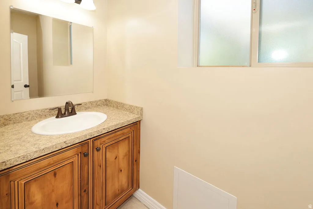 Vanity with wood cabinetry, speckled countertop, and integrated oval sink