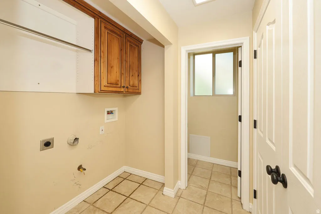 Laundry area featuring upper cabinetry, a hanging rod, and tile flooring