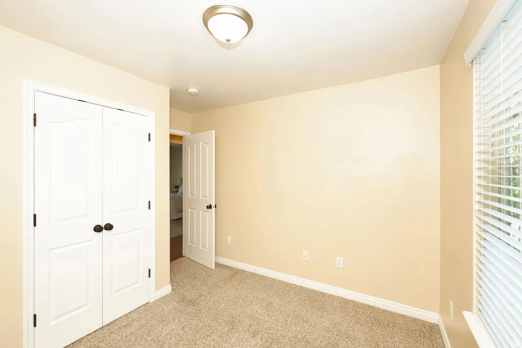 Neutral-toned room featuring light beige walls and a textured carpet
