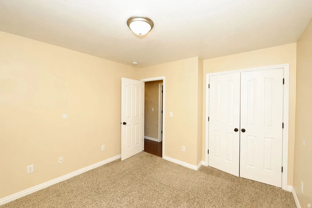 Carpeted interior room featuring light-toned walls, white trim, and a white six-panel door