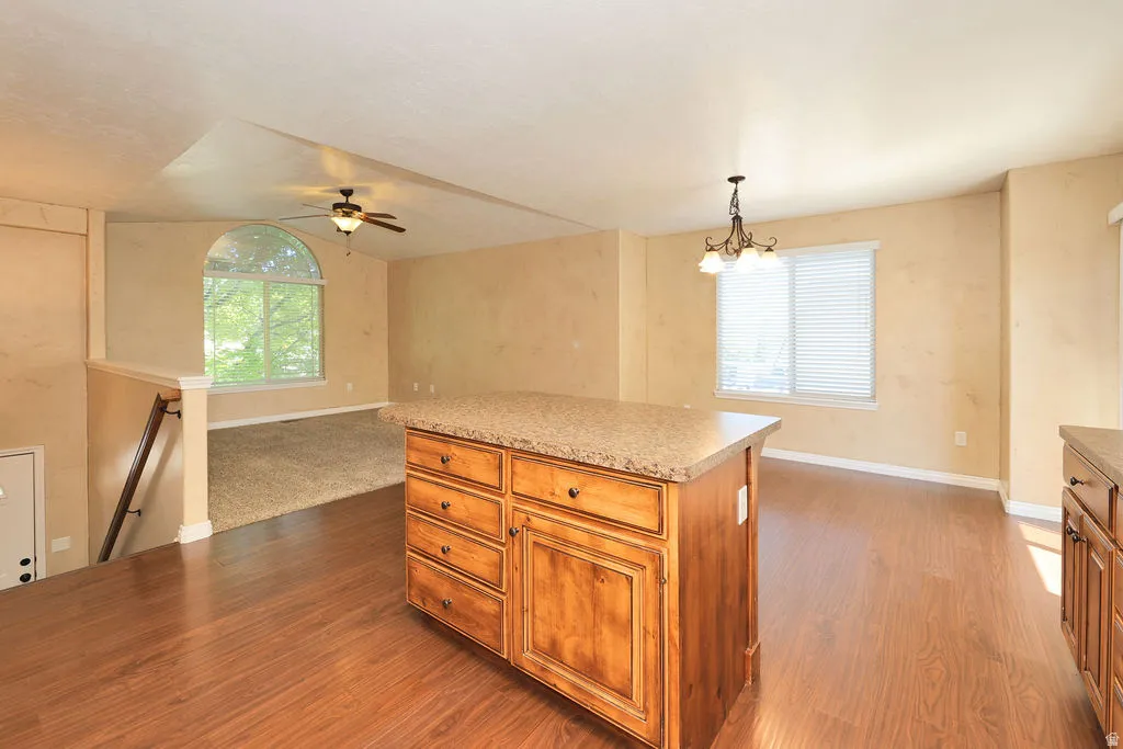 Kitchen island with wood cabinetry and a speckled countertop