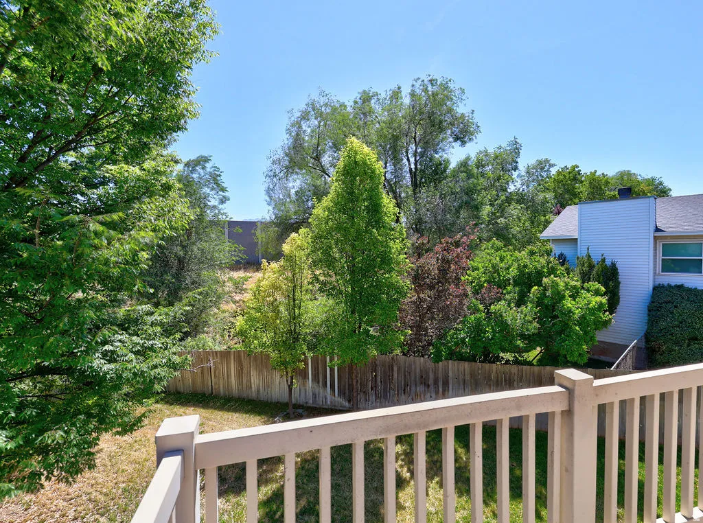 Private outdoor space featuring a wood fence, mature trees, and landscaping