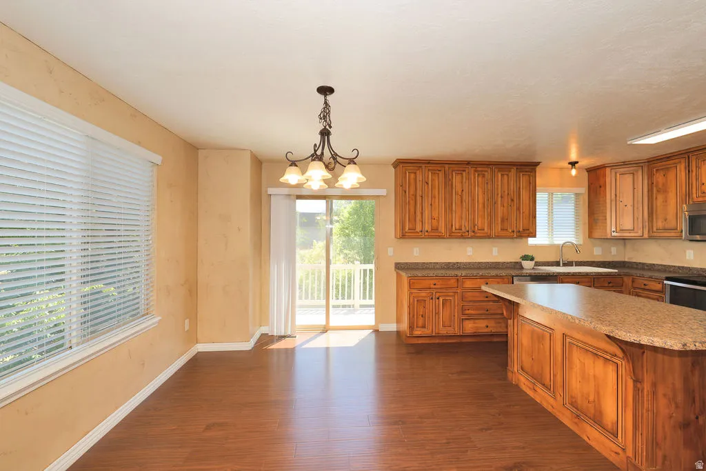 Open-concept kitchen and dining area featuring wood-finish flooring, custom wood cabinetry, and a central island with an integrated sink