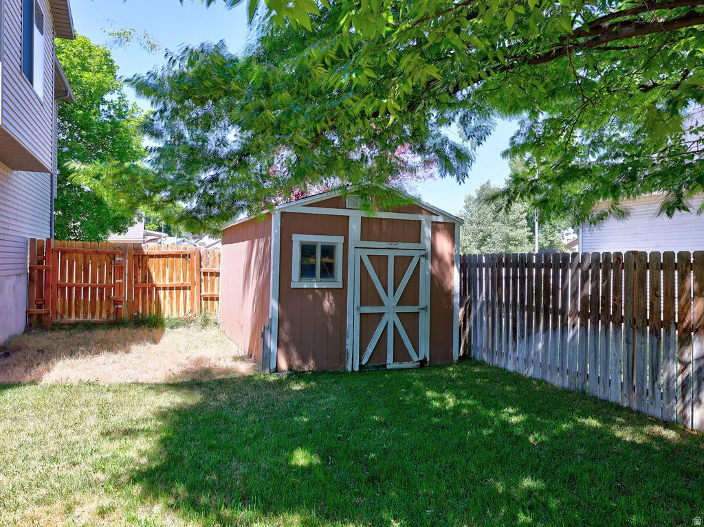Fenced backyard featuring a storage shed with a window and a cross-brace door
