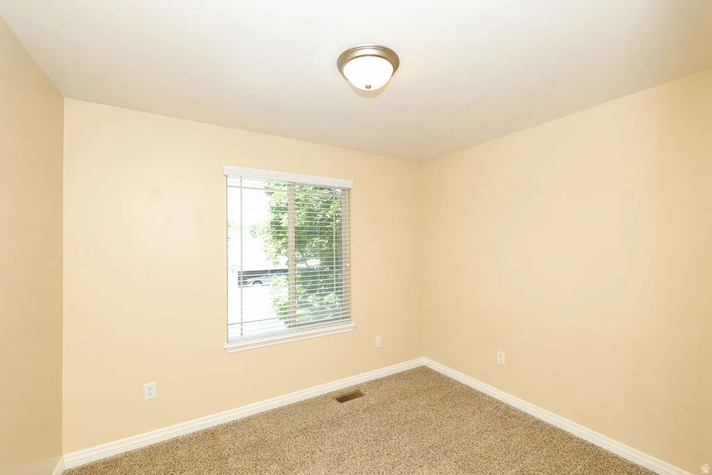 Carpeted room with a window, white blinds, and a semi-flush mount ceiling light fixture