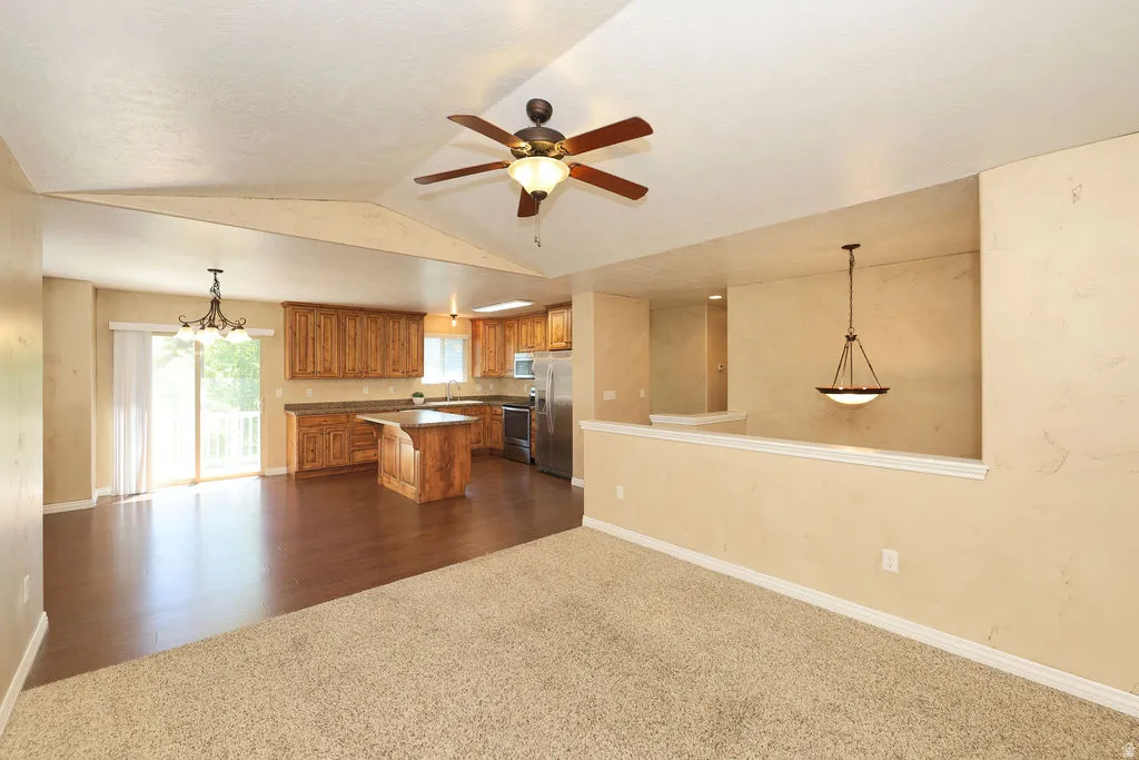 Open-concept living space featuring a kitchen with wood cabinetry and stainless steel appliances