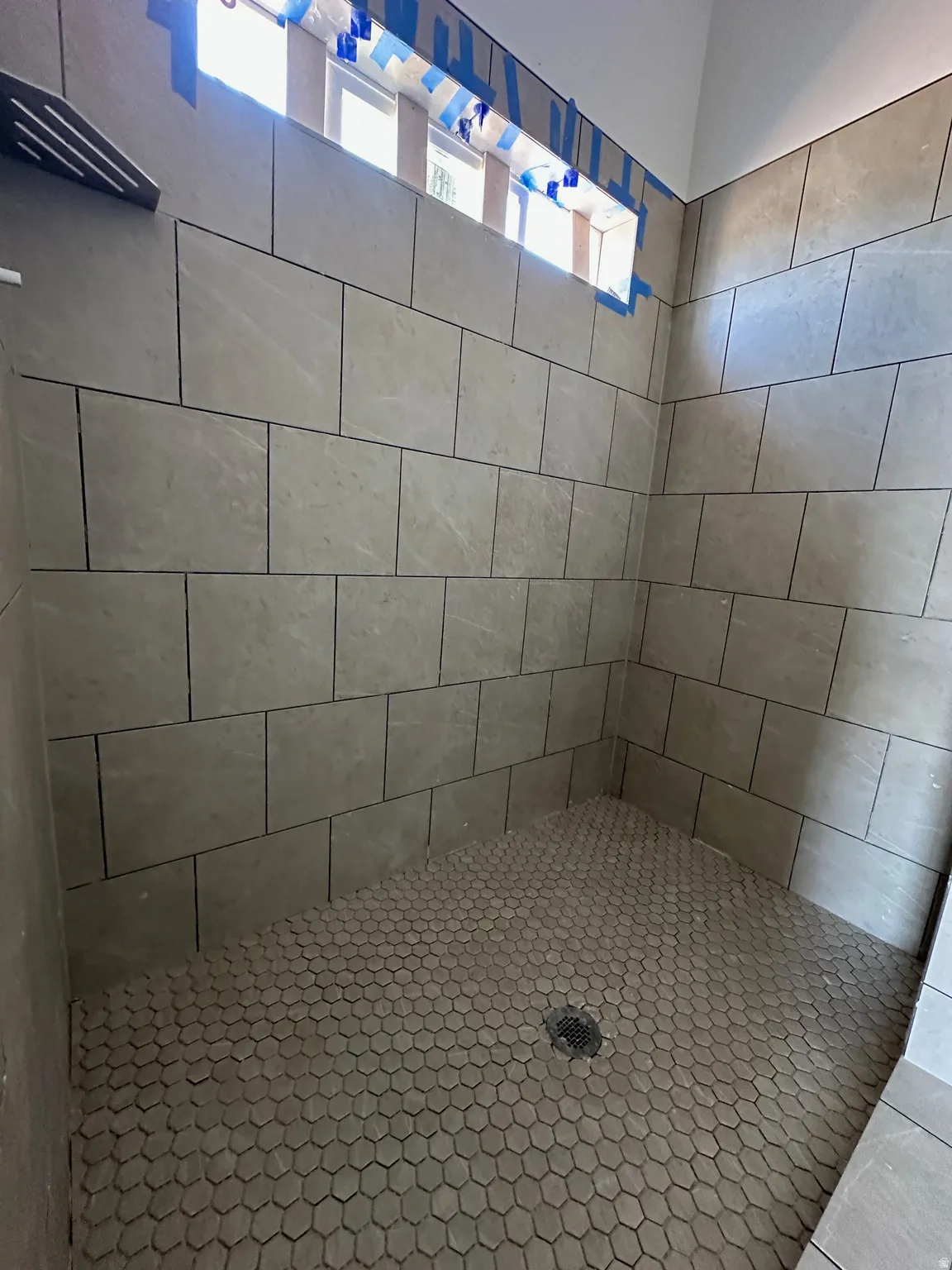 Walk-in shower featuring rectangular wall tiles, hexagonal floor tiles, and a contemporary rain shower head