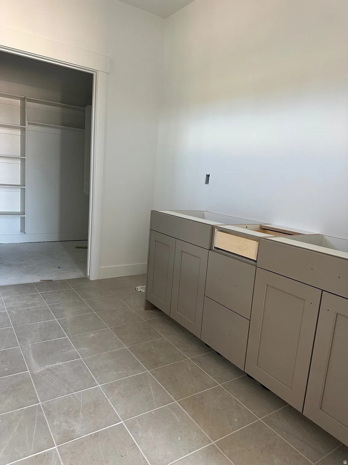 Spacious room with a neutral tile flooring and contemporary base cabinetry featuring shaker-style doors