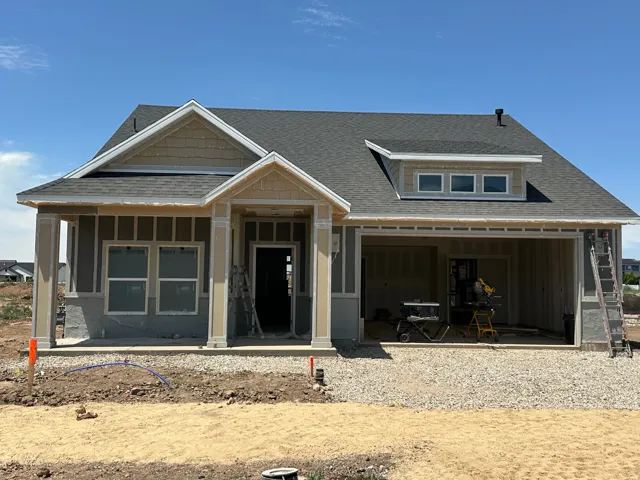 New construction residence featuring a composition shingle roof, dormer window, front porch with columns, and an attached garage structure
