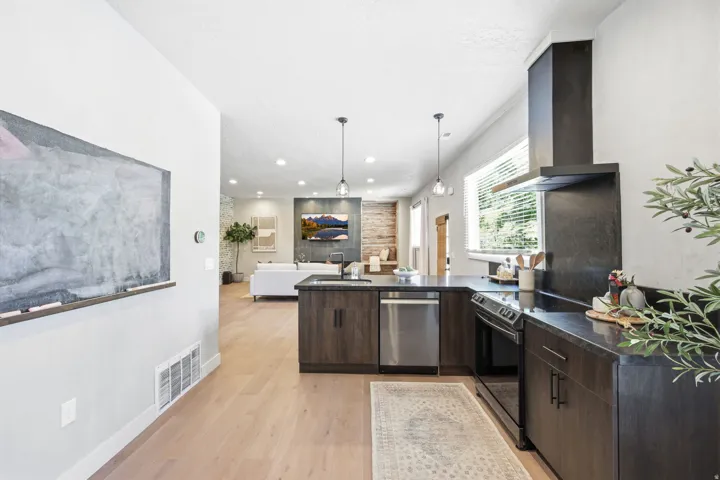 Open-concept kitchen featuring dark wood-finish cabinetry, dark countertops, and stainless steel appliances