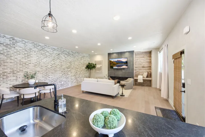 Open concept living area featuring wood-finish flooring, recessed lighting, and a whitewashed brick accent wall
