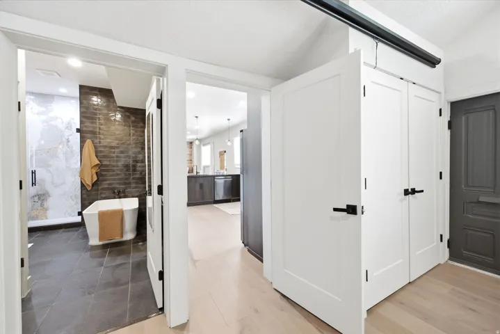Contemporary bathroom featuring a freestanding tub, dark subway tile accent wall, and a spacious glass-enclosed shower with large format marble-patterned tile