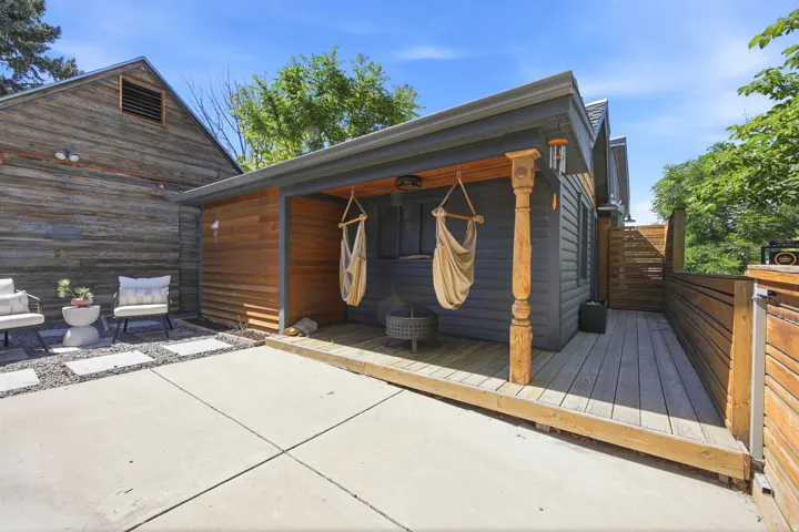 Covered porch area with a wood-finish deck, plank siding, and carved wood column