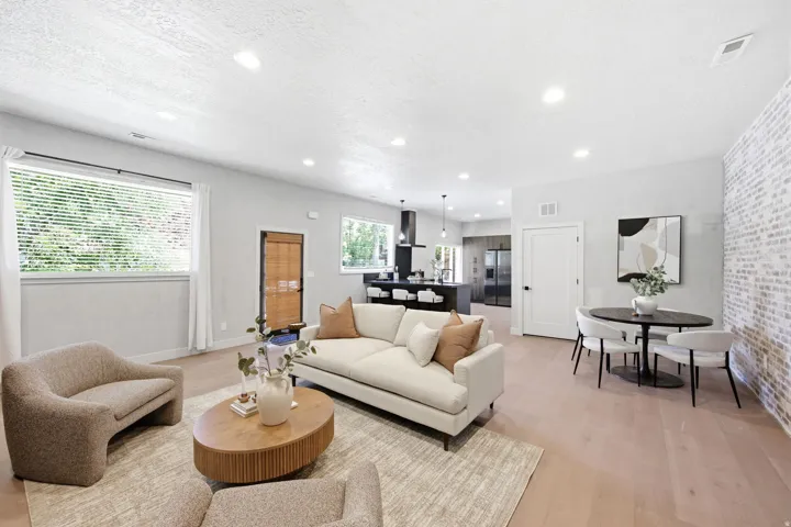 Open-concept living space featuring light wood-finish flooring, recessed lighting, and a white-washed brick accent wall