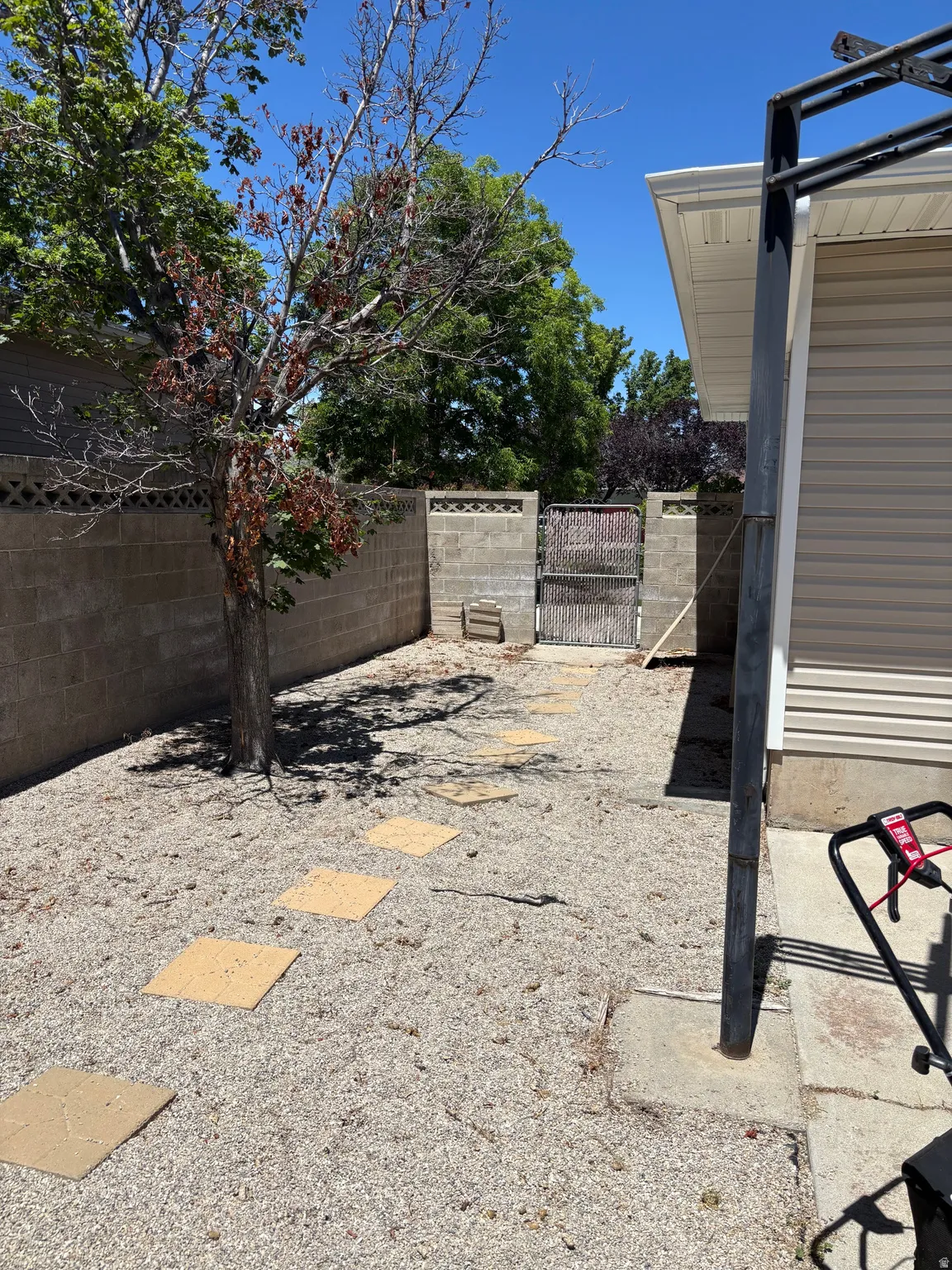 Gravel yard with square stepping stones, bordered by a concrete block wall