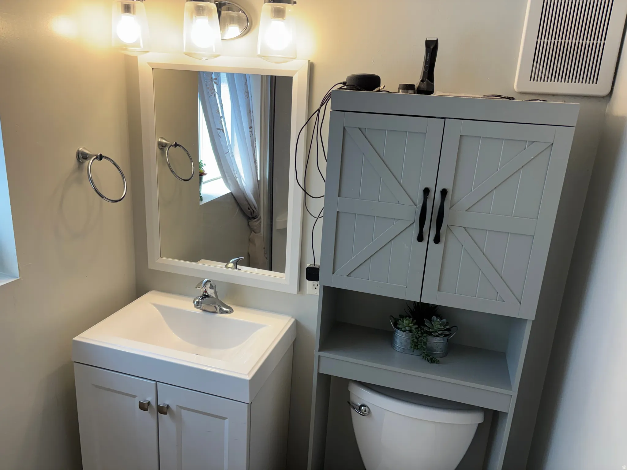 Bathroom featuring a white vanity with integrated sink, coordinating wall-mounted mirror, and a three-light vanity fixture