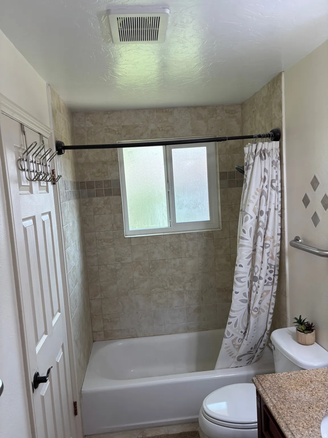 Bathroom with tiled shower surround, integrated bathtub, and a window for natural light