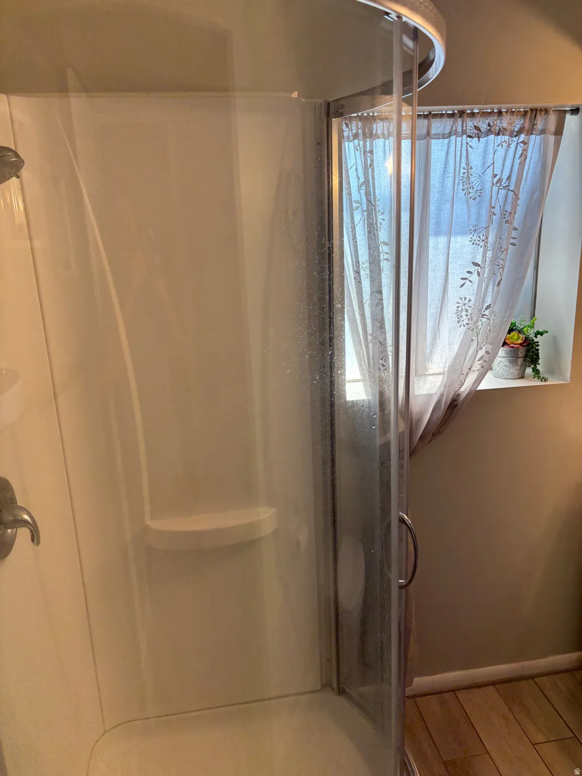 Curved glass shower enclosure with chrome hardware and integrated shelving