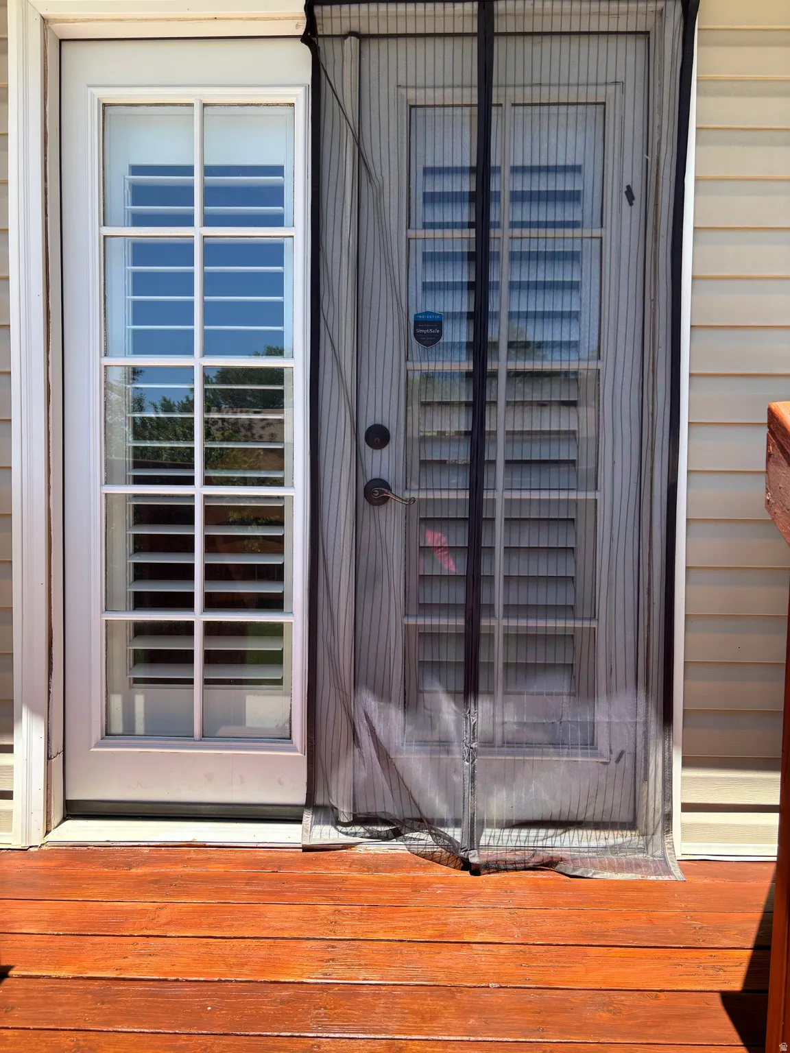Wood-finish deck with a white multi-pane glass door and an exterior door with a screen