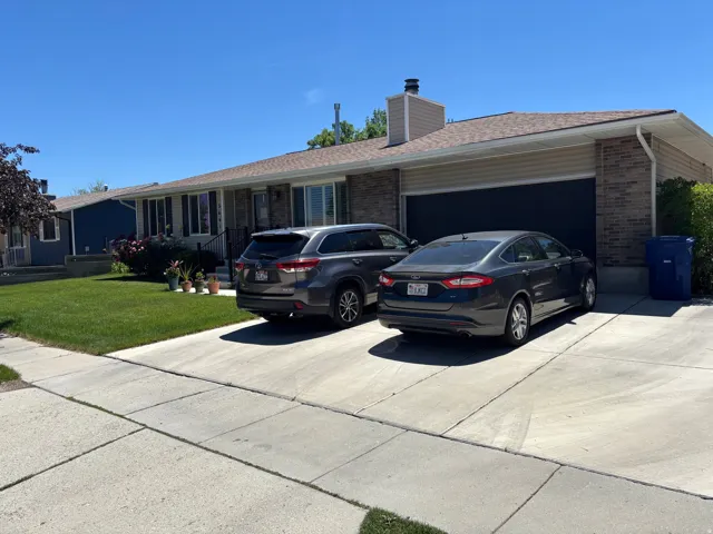 Ranch-style exterior with a two-car garage, brick facade, and tan siding