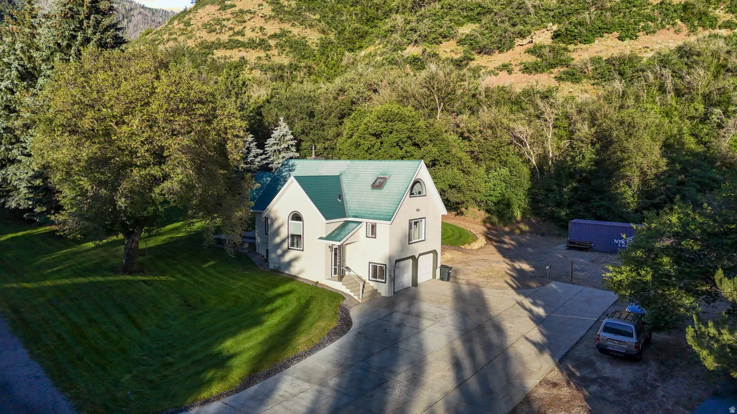 Two-story residence with a prominent green roof, featuring a two-car garage, arched windows, and a concrete driveway