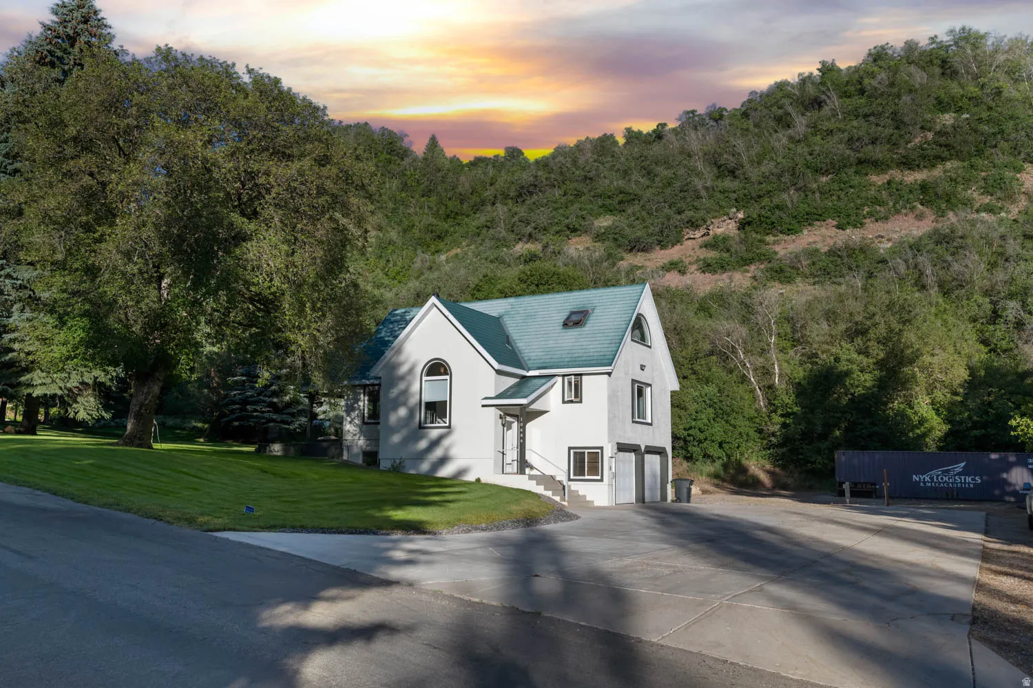 White stucco exterior with a teal shingle roof and dormer window