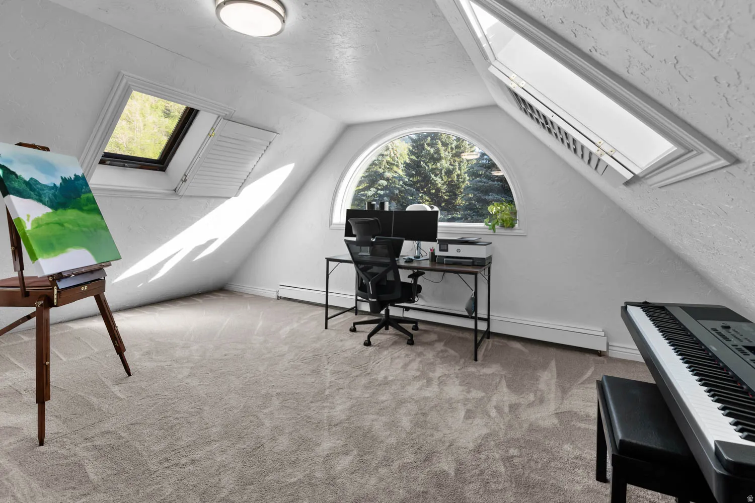 Versatile room featuring vaulted ceilings, a large arched window, two skylights, textured walls, and neutral carpeting