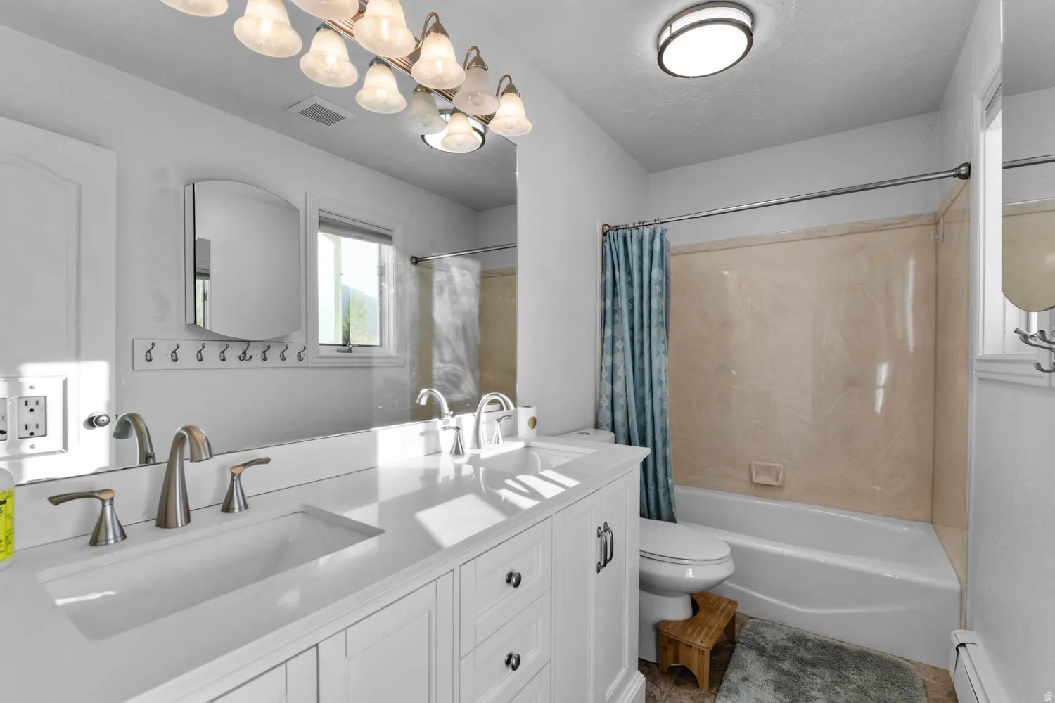 Bathroom featuring a dual vanity with integrated sinks, brushed nickel fixtures, and white cabinetry