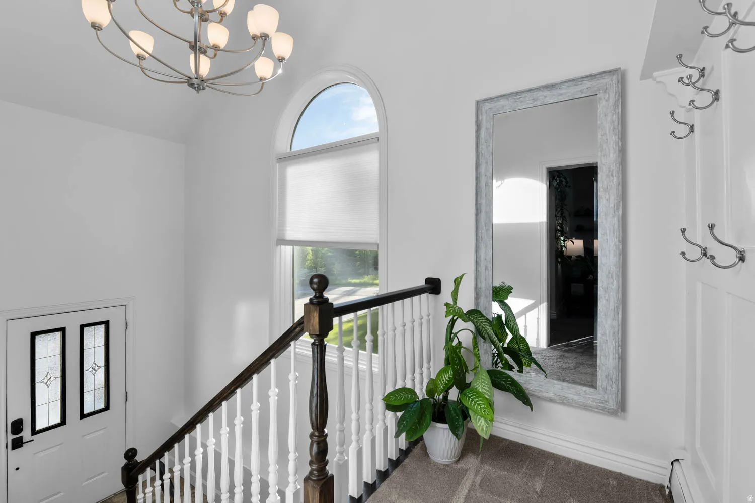 Arched window providing natural illumination, complemented by a contemporary chandelier
