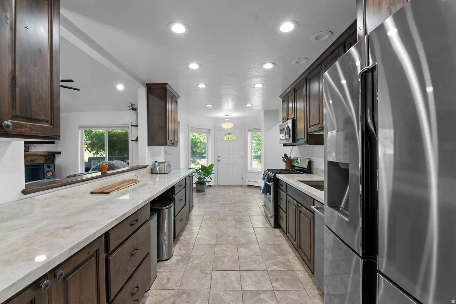 Modern kitchen featuring dark wood cabinetry, light-toned countertops, and stainless steel appliances
