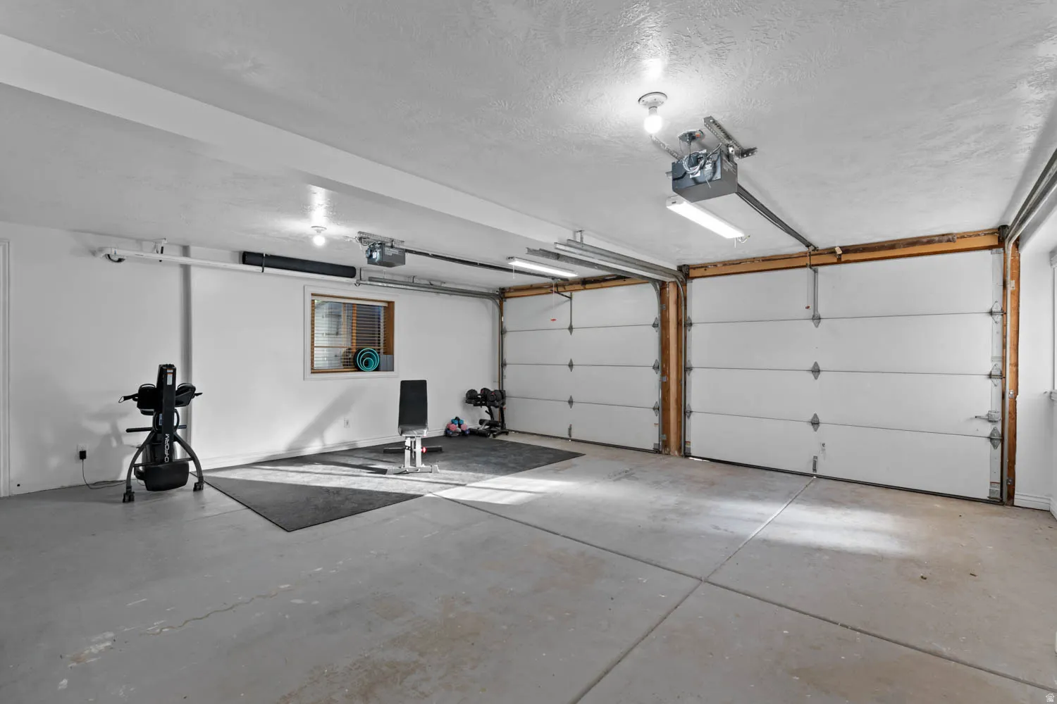 Two-car garage featuring a concrete floor, white walls, and a window for natural light