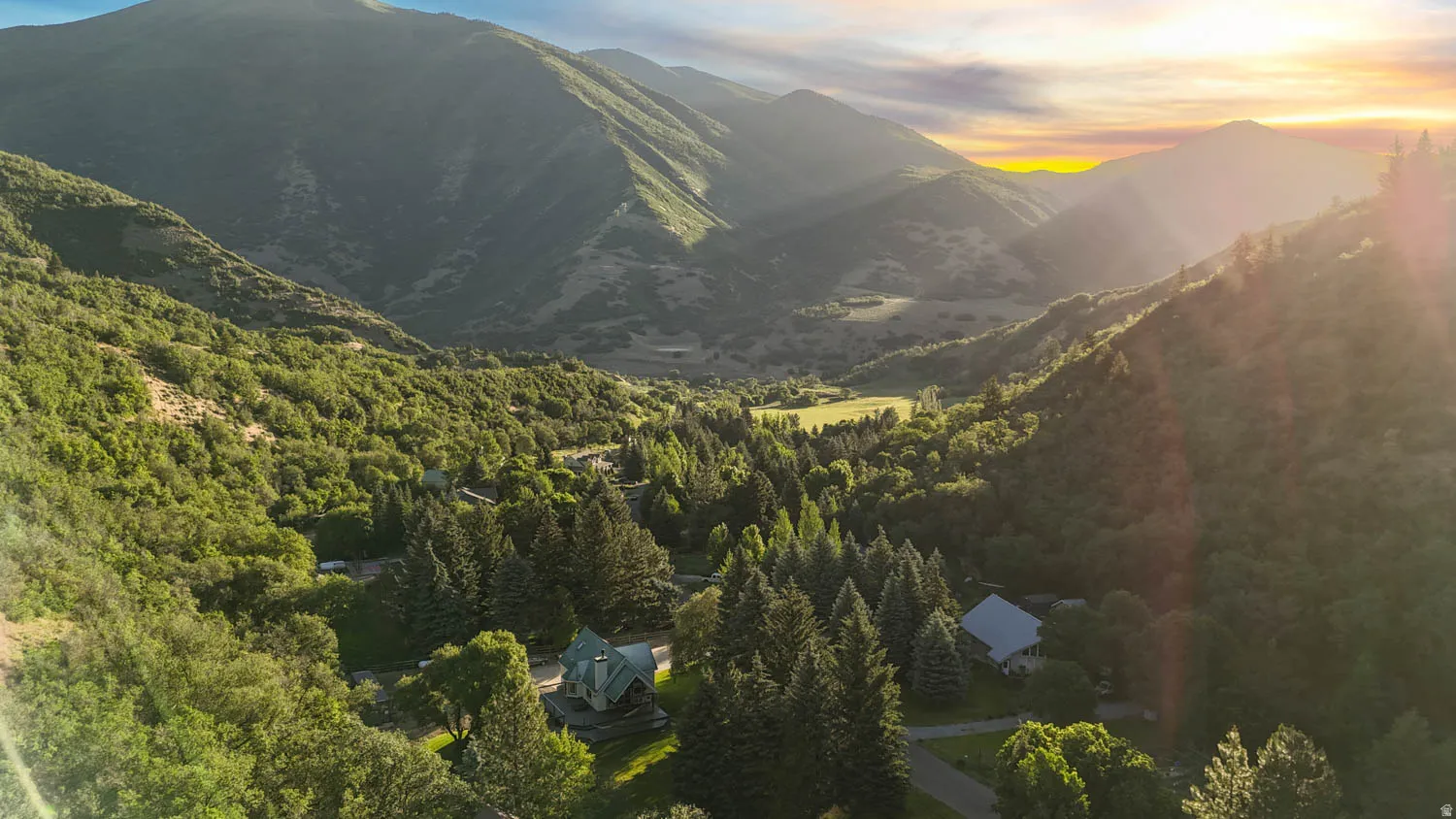 Expansive valley setting featuring lush forested hillsides and a distant residential structure