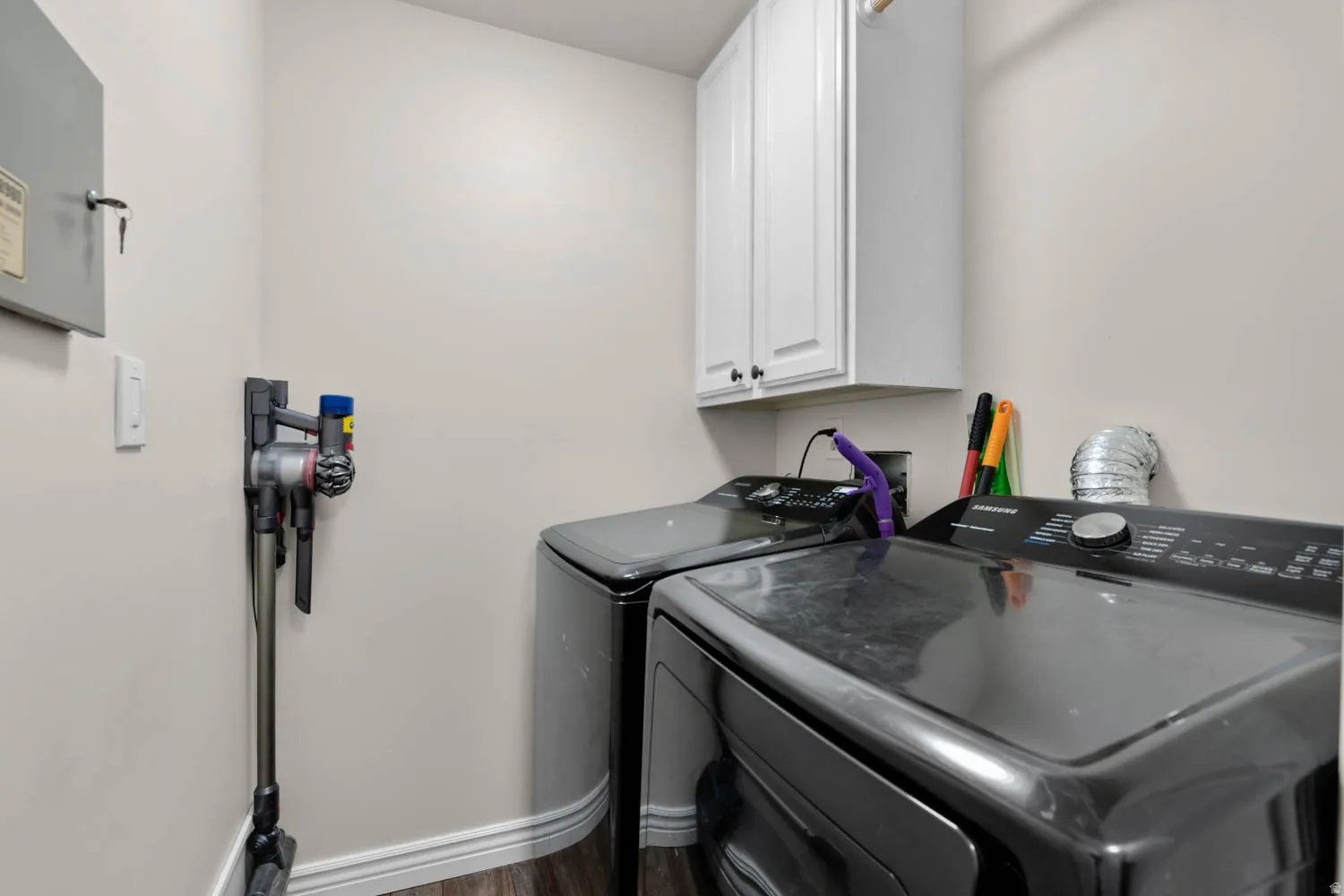 Dedicated laundry area featuring wood-finish flooring and white baseboards
