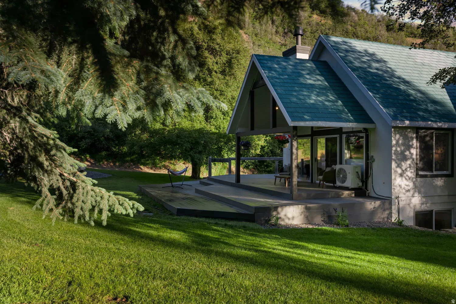 A-frame style residence with a pitched roof, featuring an expansive deck and exterior wood railing