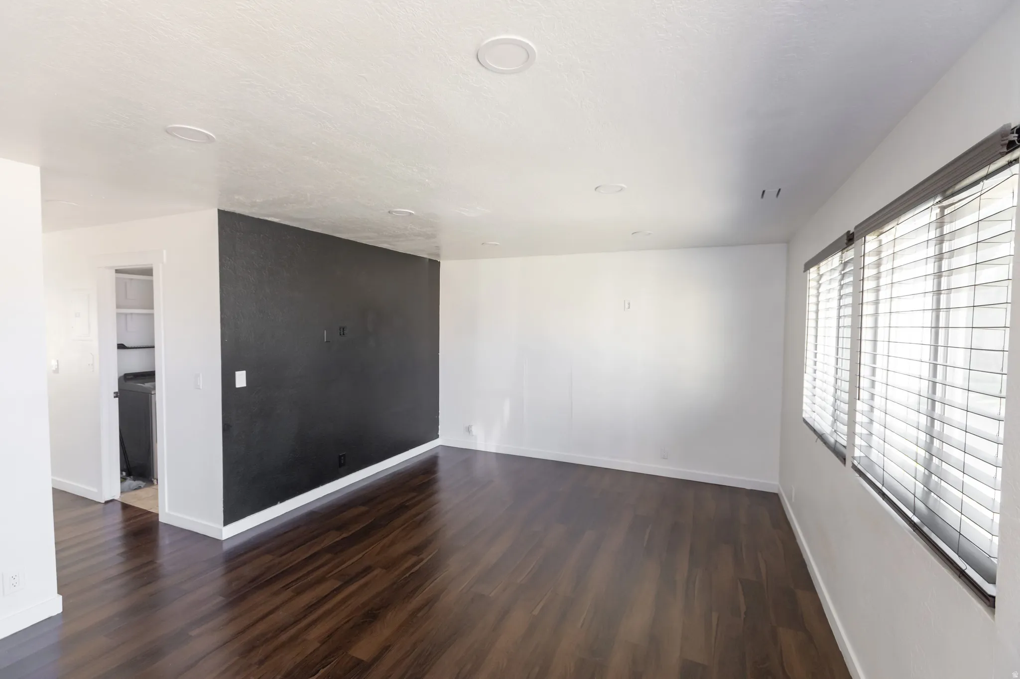 Spacious room featuring rich wood-finish flooring and a distinctive accent wall
