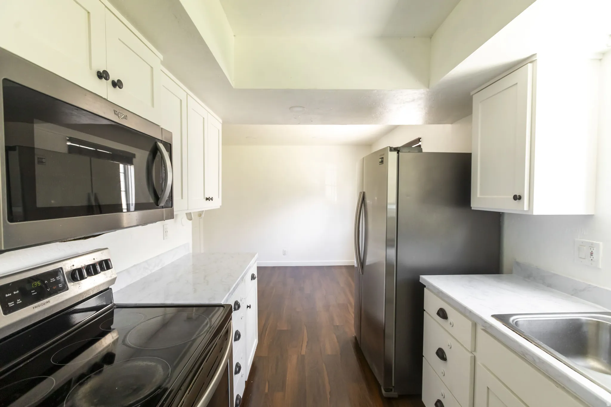 Kitchen featuring white cabinetry, stainless steel appliances, white countertops, and wood-finish flooring