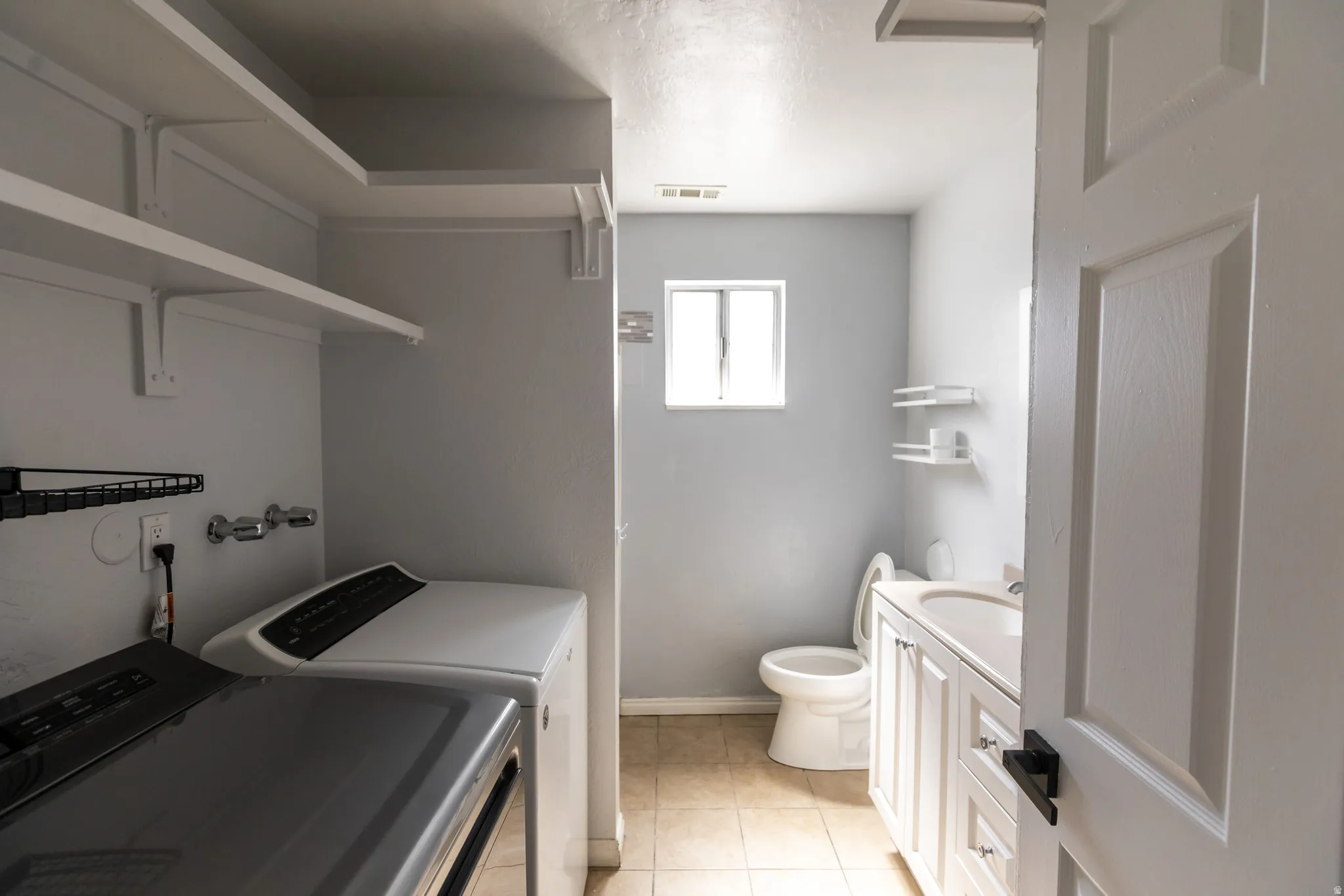 Utility area featuring built-in shelving, a dedicated laundry space, and a separate bathroom