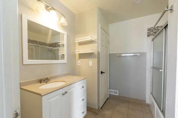 Bathroom featuring a single vanity with an integrated sink, framed mirror, and track lighting
