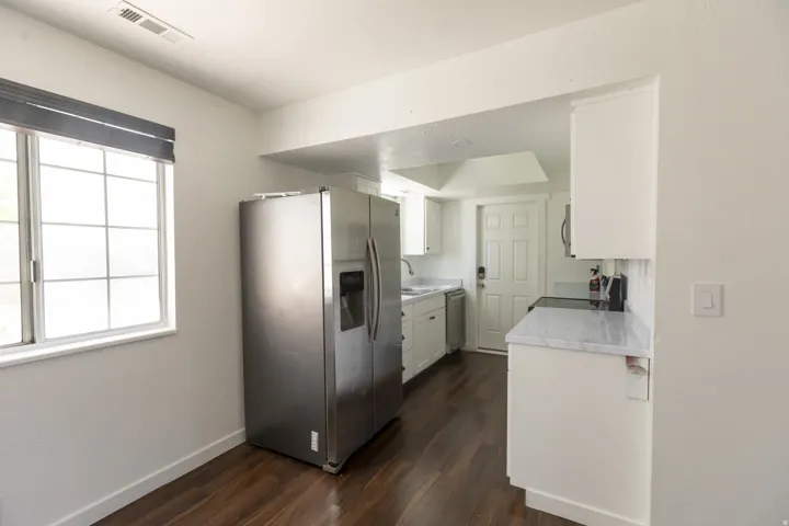 Bright kitchen space featuring wood-finish flooring, white cabinetry, and stainless steel appliances