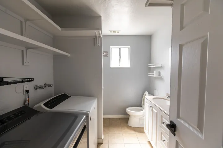 Utility area featuring built-in shelving, a dedicated laundry space, and a separate bathroom