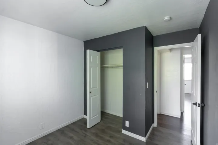 Room featuring gray wood-finish flooring, white baseboards, and a neutral color palette with white and dark gray walls