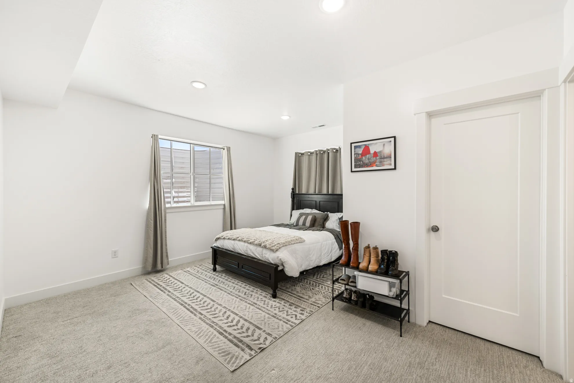 Bedroom featuring a window with horizontal blinds, overhead recessed lighting, light-colored carpeting, and a white panel door