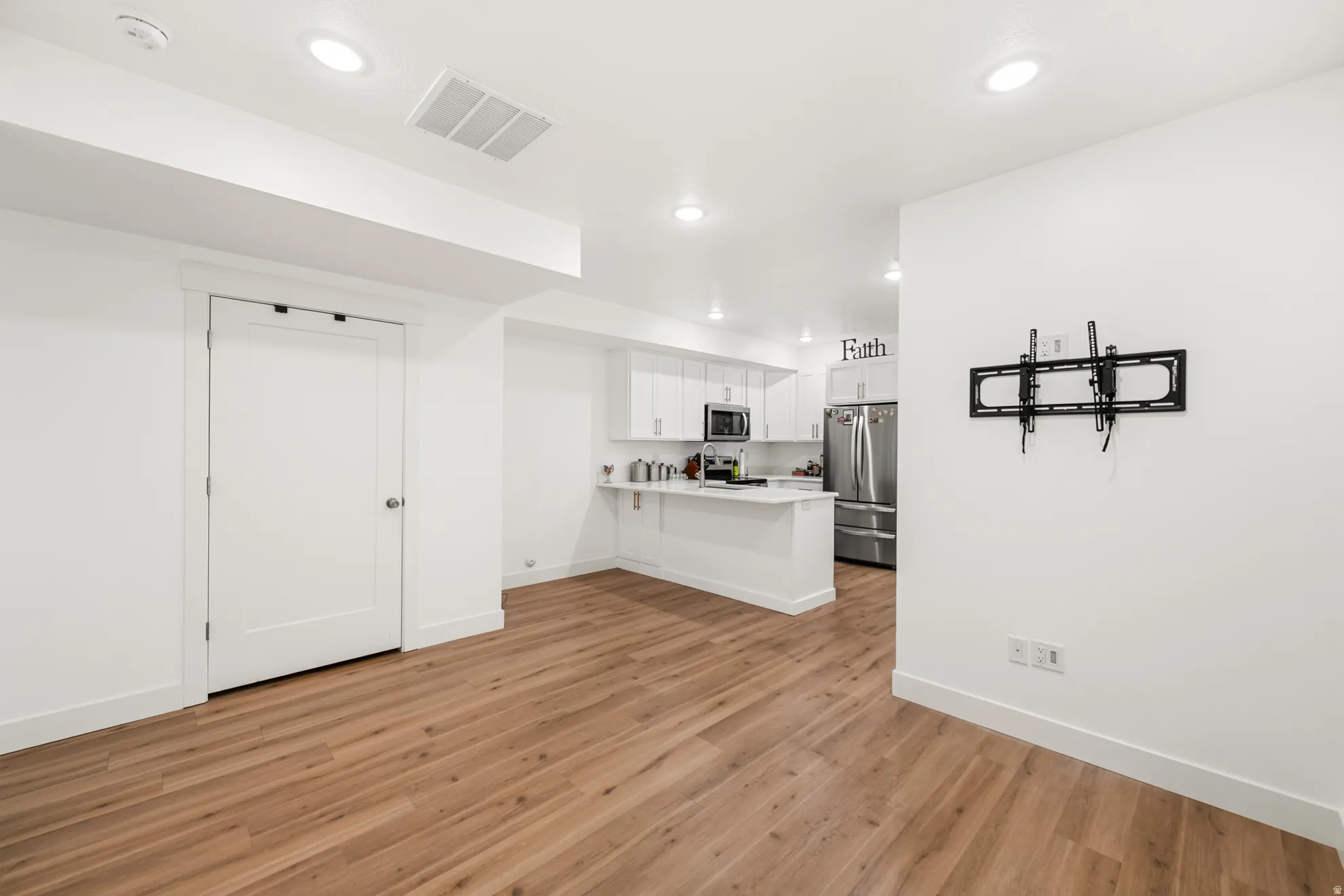 Open-concept living area featuring wood-finish flooring, recessed lighting, and a modern kitchen