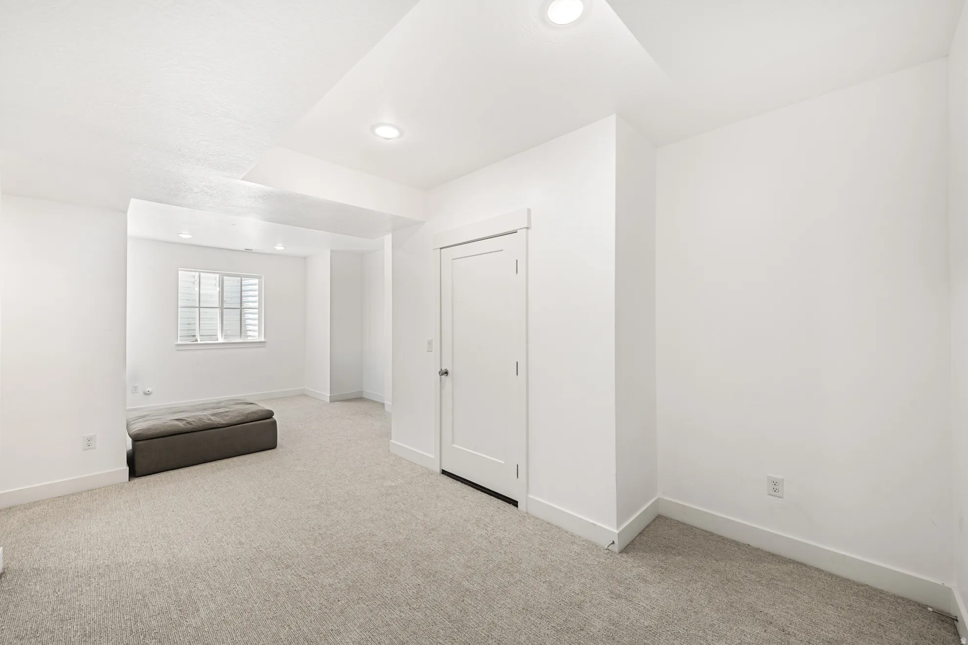 Carpeted interior space featuring recessed lighting, a window with horizontal blinds, and a white interior door