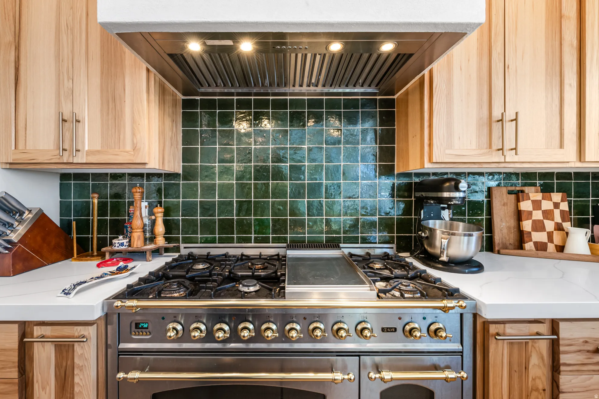 Professional-grade range with brass accents, set against a vibrant green tile backsplash