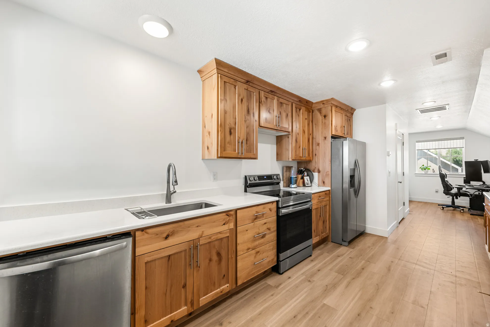 Kitchen featuring wood cabinetry, stainless steel appliances, white countertops, and wood-finish flooring
